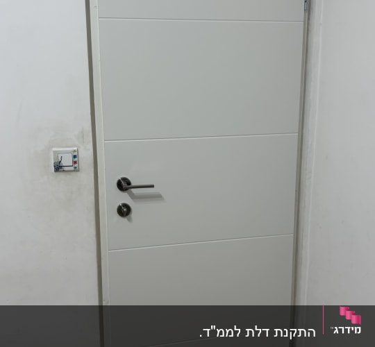 דלת לבנה עם ידית מתכת על קיר לבן